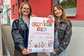 Zwei Frauen präsentieren ein buntes Plakat.