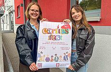 Zwei Frauen präsentieren ein buntes Plakat.
