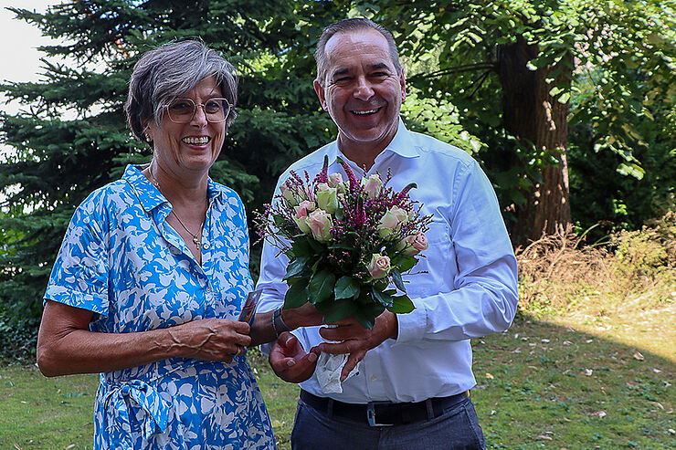 Ein Mann überreicht einer Frau Blumen und einen Geschenkgutschein.