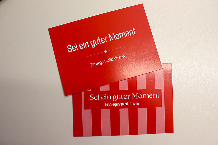 Zwei Postkarten mit der Aufschrift Sei ein guter Moment liegen nebeneinander.