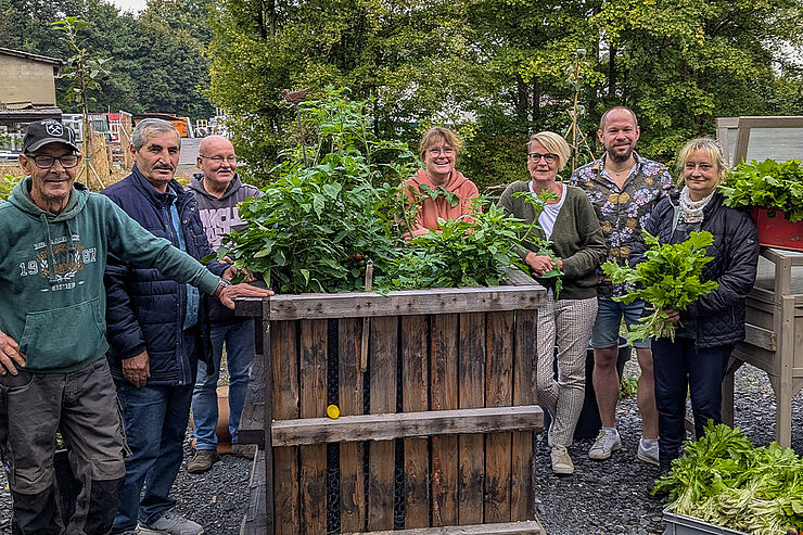 Eine Gruppe Menschen steht bei einem bepflanzten Hochbeet.