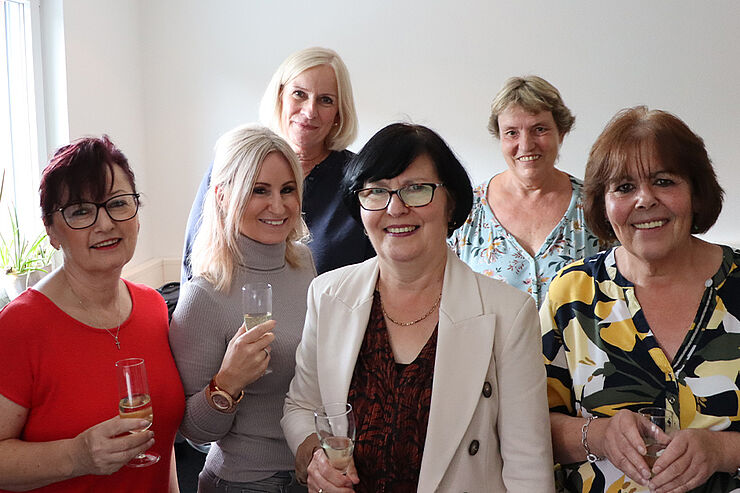 Sechs Frauen stehen mit Sektgläsern zusammen.