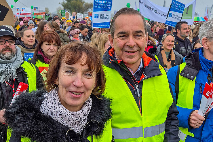 Eine Frau und ein Mann stehen vor mehreren Menschen.