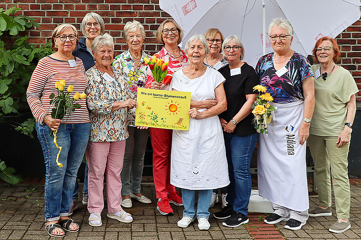 Zehn Frauen stehen zusammen und lächeln.