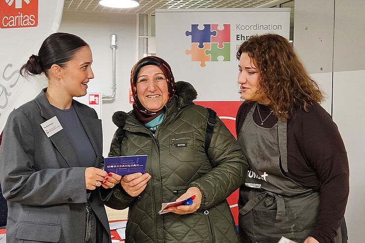 Drei Frauen stehen zusammen und sprechen miteinander.